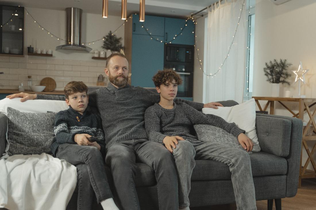 un père et ses enfants sont assis sur le canapé